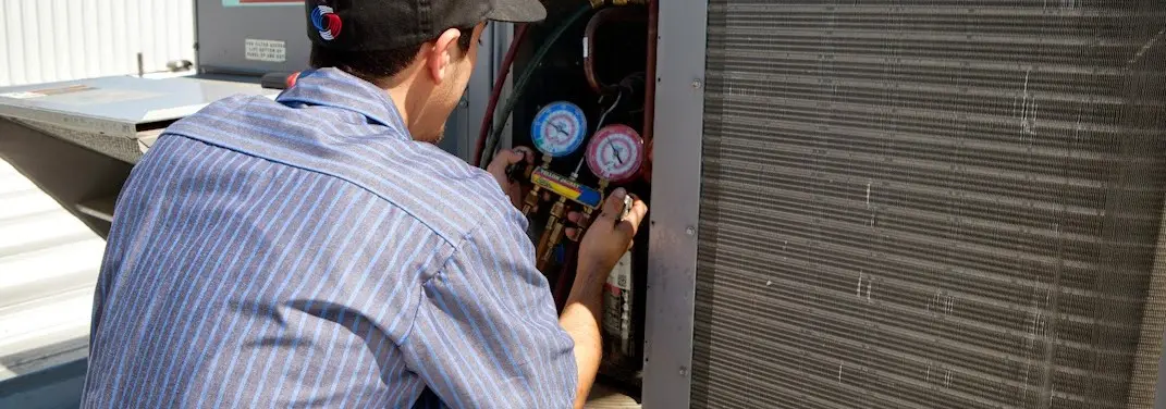 HVAC technician servicing a condenser unit in Grimes