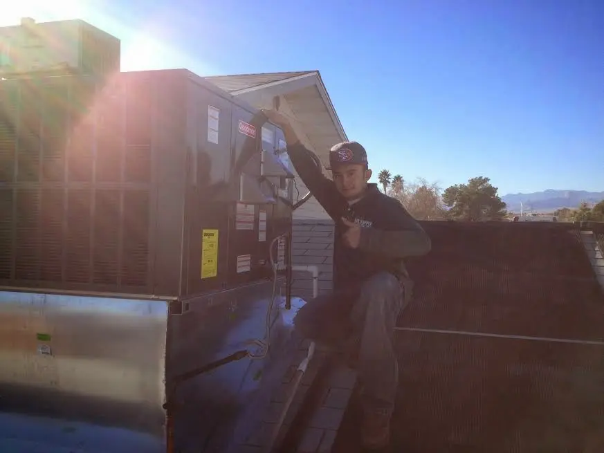 HVAC technician performing Air Duct Repair on a rooftop unit in Grimes